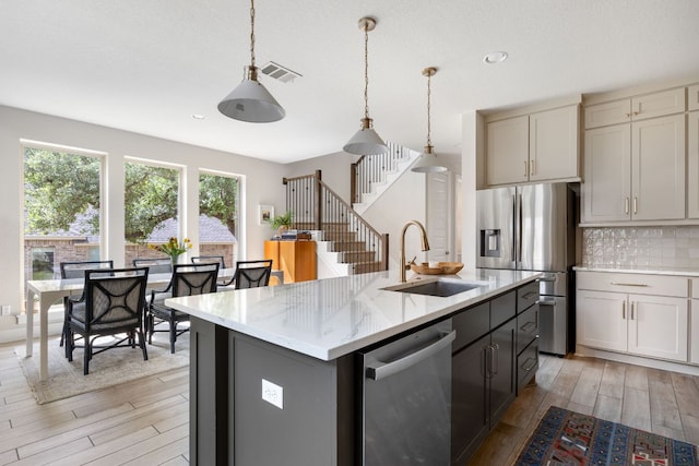 229 S Park Vis, Georgetown, TX 78628 - kitchen featuring stainless steel appliances, a sink, light wood finished floors, tasteful backsplash, and pendant lighting