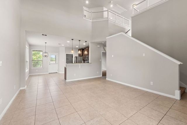 unfurnished living room featuring stairway, baseboards, a towering ceiling, and light tile patterned floors
