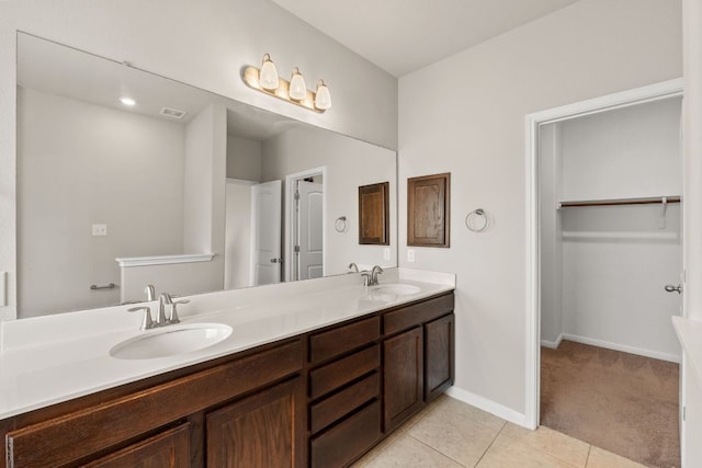 full bath featuring double vanity, tile patterned floors, baseboards, and a sink