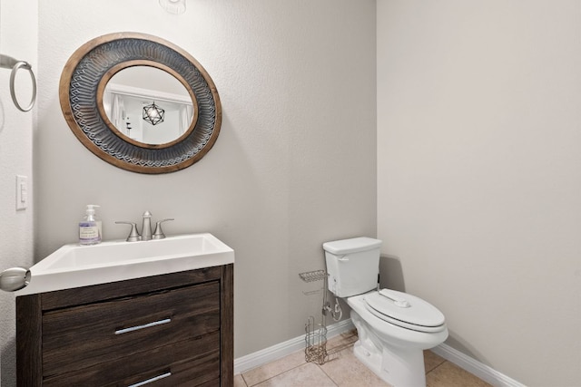 half bathroom featuring vanity, tile patterned floors, baseboards, and toilet