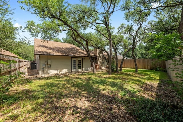 view of yard featuring a fenced backyard, french doors, and cooling unit