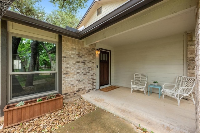 entrance to property featuring brick siding and a patio