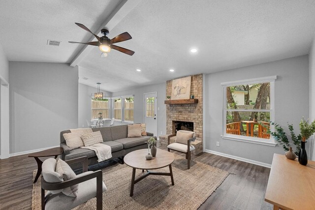 living area featuring a ceiling fan, visible vents, a fireplace, baseboards, and dark wood-style floors