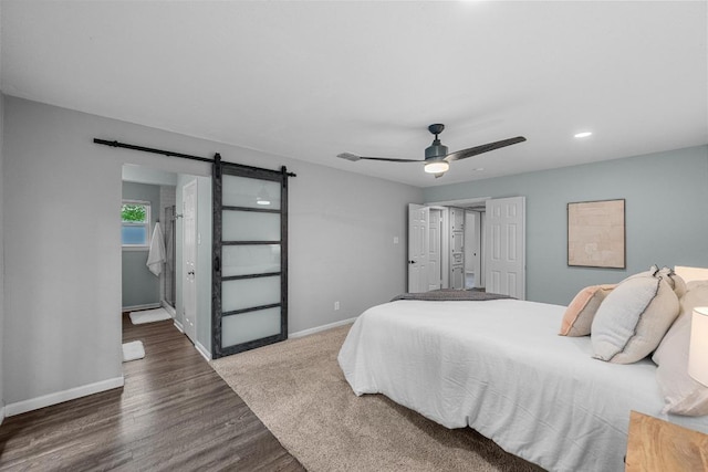 bedroom with baseboards, a ceiling fan, wood finished floors, and a barn door