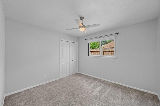 unfurnished bedroom with baseboards, carpet, a closet, and ceiling fan