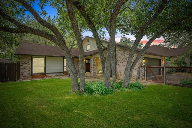 view of front of home with brick siding, fence, a front yard, and an attached garage