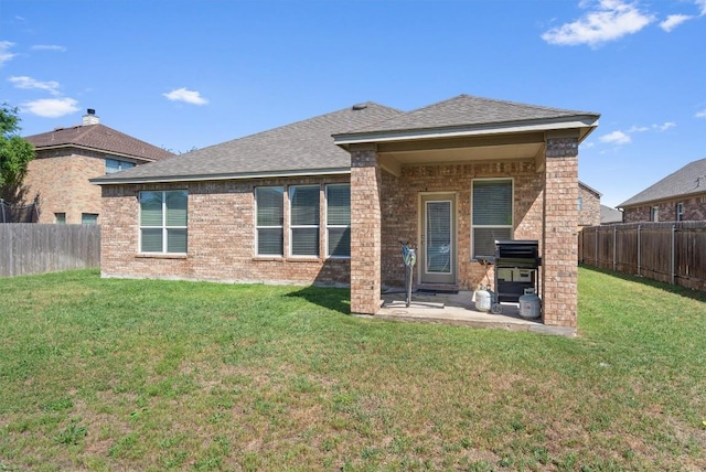 rear view of property with a lawn, a fenced backyard, brick siding, and a patio