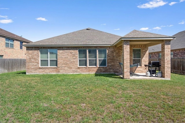rear view of house featuring a fenced backyard, brick siding, a yard, and a patio