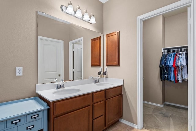 full bath featuring a spacious closet, baseboards, a sink, and double vanity