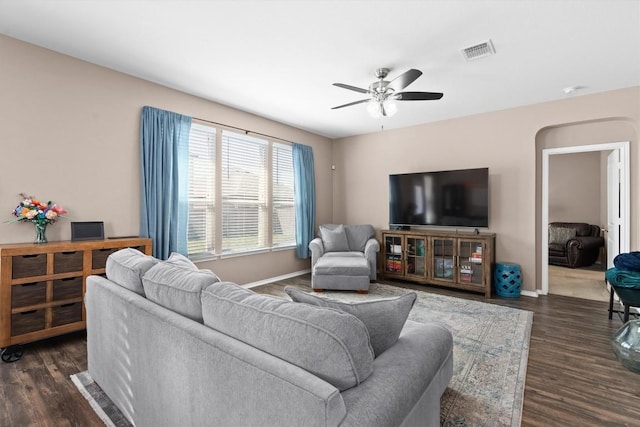 living room featuring dark wood finished floors, visible vents, baseboards, and ceiling fan