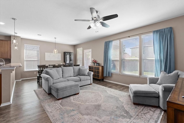 living area featuring wood finished floors, baseboards, and ceiling fan