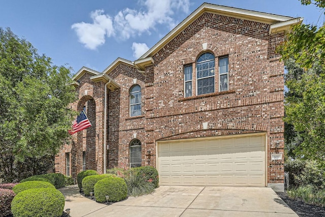traditional-style house with concrete driveway, brick siding, and a garage