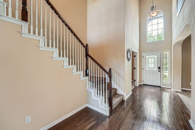 foyer featuring dark wood finished floors, stairway, a towering ceiling, and baseboards