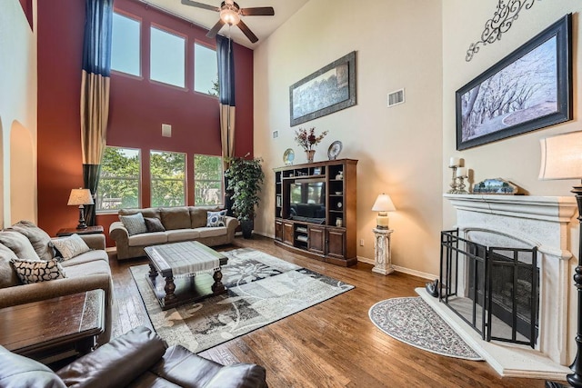 living area with a ceiling fan, wood finished floors, arched walkways, a towering ceiling, and visible vents