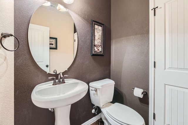 bathroom with a textured wall and toilet