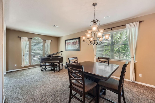 carpeted dining space featuring baseboards, visible vents, and an inviting chandelier