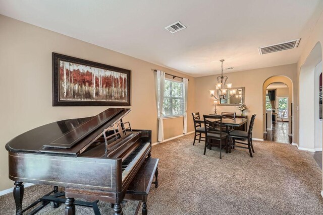 carpeted dining area with a wealth of natural light, arched walkways, visible vents, and baseboards
