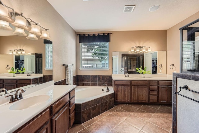 bathroom featuring a garden tub, tile patterned flooring, a sink, and visible vents