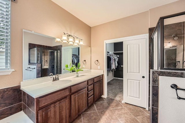 bathroom with a spacious closet, a tile shower, vanity, and tile patterned floors