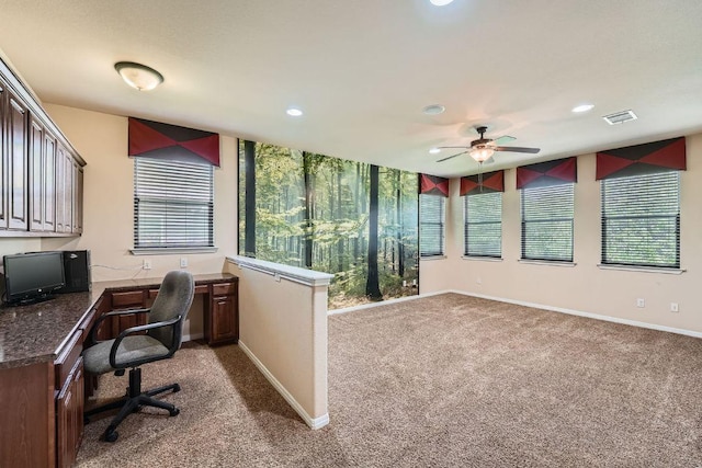 home office with carpet, visible vents, a ceiling fan, and a wealth of natural light