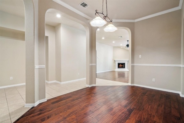 1124 Dyer Creek Pl, Round Rock, TX 78665 - unfurnished dining area with hardwood / wood-style flooring, arched walkways, crown molding, baseboards, and a lit fireplace