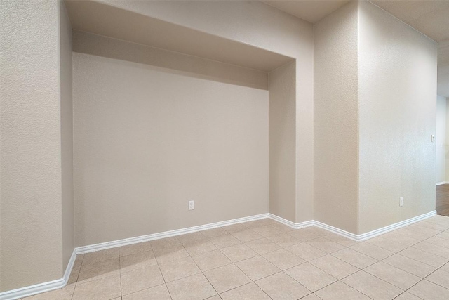 empty room with light tile patterned flooring and baseboards