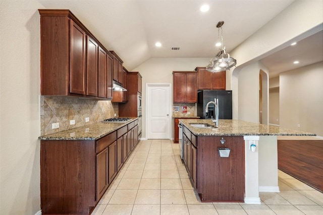 kitchen featuring arched walkways, dark stone countertops, appliances with stainless steel finishes, and tasteful backsplash