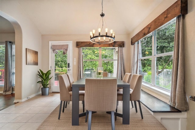 dining room featuring baseboards, arched walkways, light tile patterned floors, a notable chandelier, and vaulted ceiling