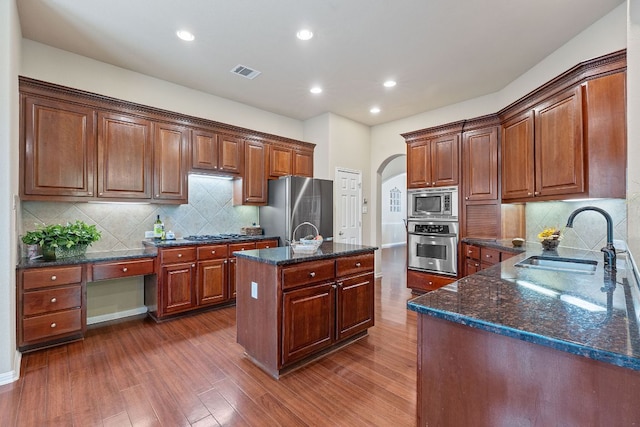 10033 Lisi Anne Dr, Austin, TX 78717 - kitchen featuring stainless steel appliances, arched walkways, dark wood-style floors, dark stone counters, and recessed lighting