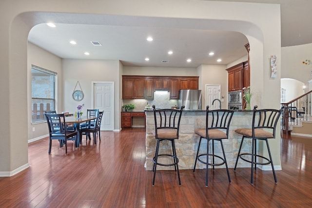 10033 Lisi Anne Dr, Austin, TX 78717 - kitchen featuring appliances with stainless steel finishes, arched walkways, a kitchen bar, a peninsula, and recessed lighting