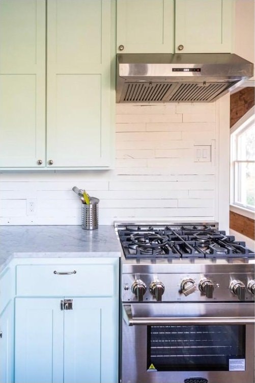 712 Harris Ave Unit 1, Austin, TX 78705 - kitchen with under cabinet range hood, high end stainless steel range oven, light stone counters, and decorative backsplash