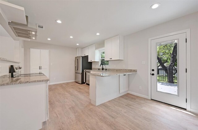 7611 Oak Hedge Pl, Austin, TX 78745 - kitchen featuring appliances with stainless steel finishes, a sink, a peninsula, white cabinets, and light wood-style flooring