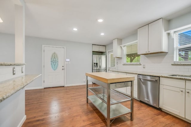 kitchen featuring wood finished floors, decorative backsplash, white cabinets, appliances with stainless steel finishes, and recessed lighting