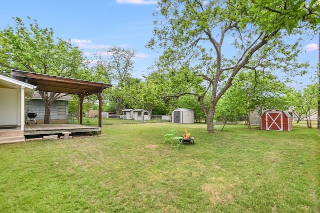 view of yard featuring an outdoor structure, fence, a wooden deck, and a shed