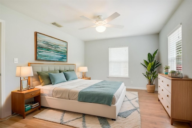 bedroom with light wood-type flooring, visible vents, a ceiling fan, and baseboards