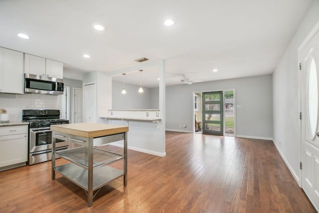 kitchen featuring visible vents, a ceiling fan, baseboards, decorative backsplash, and appliances with stainless steel finishes