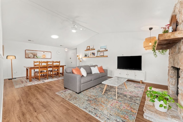 living room with baseboards, visible vents, lofted ceiling, wood finished floors, and ceiling fan