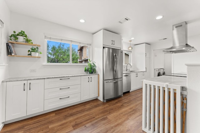 kitchen with white cabinets, stainless steel appliances, island exhaust hood, visible vents, and washer and dryer
