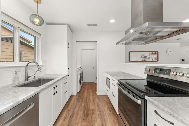 kitchen featuring a sink, light wood-style flooring, wall chimney exhaust hood, appliances with stainless steel finishes, and visible vents