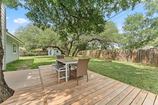 wooden deck with a fenced backyard, a storage shed, a yard, outdoor dining space, and an outbuilding