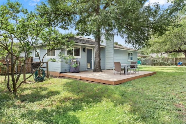 rear view of house featuring a lawn, a wooden deck, a fenced backyard, and a chimney