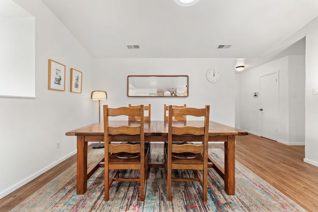 dining area with baseboards, wood finished floors, and visible vents