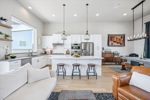 6229 Florencia Ln, Austin, TX 78724 - kitchen with open floor plan, stainless steel appliances, a kitchen breakfast bar, white cabinets, and backsplash