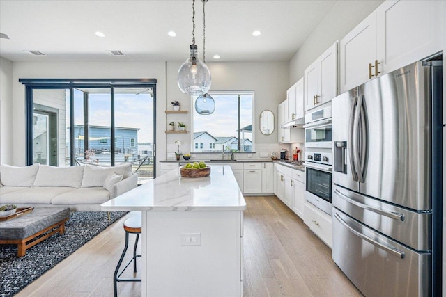 6229 Florencia Ln, Austin, TX 78724 - kitchen featuring stainless steel fridge with ice dispenser, healthy amount of natural light, recessed lighting, a kitchen island, and white cabinetry