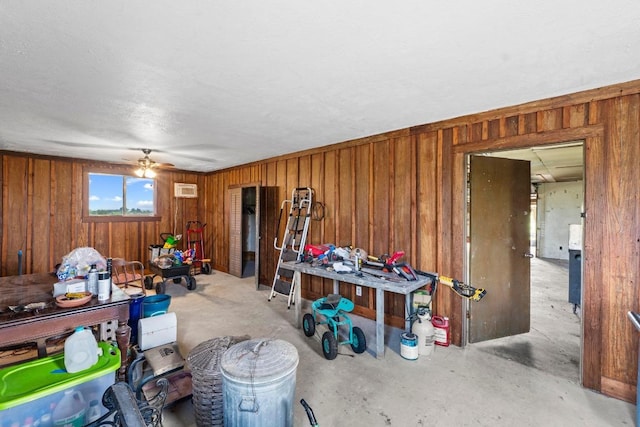interior space with wooden walls, ceiling fan, and unfinished concrete flooring