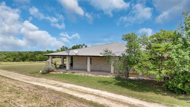 exterior space featuring metal roof, a front lawn, and stone siding