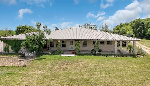 back of property featuring a lawn, fence, and metal roof
