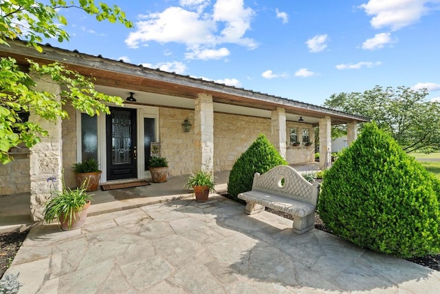 doorway to property featuring covered porch and stone siding