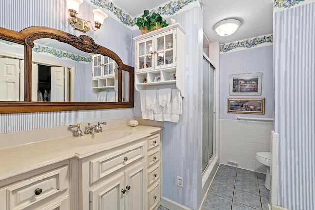 full bath with tile patterned flooring, a shower stall, and wallpapered walls