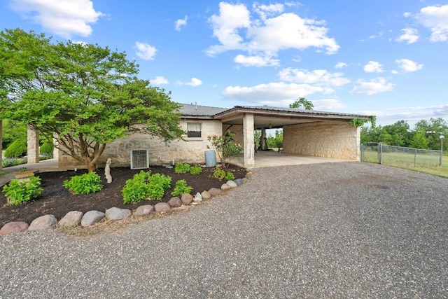 view of front of property with fence, a carport, driveway, and stone siding